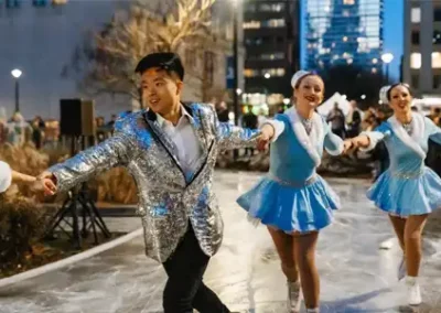 People skating on the outdoor skate trail in fancy winter themed costumes.