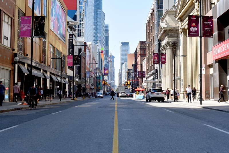 Yonge St Looking North at Queen St, with pedestrians, buildings and cars.